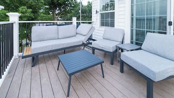 Een terras met een bank, twee stoelen en een kleine tafel.