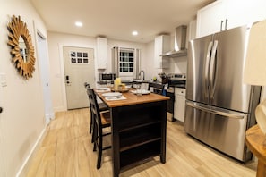 A modern kitchen with a stainless steel refrigerator, a dining table with chairs, and a microwave.