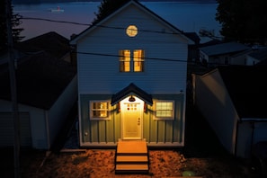 A two-story house with a front porch, a visible front door, and a small window above the door.