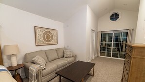 A living room with a sofa, a coffee table, a lamp, and a decorative wall piece.