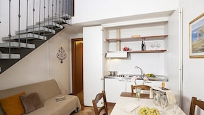 Un espacio habitable compacto con sofá, mesa de comedor y zona de cocina.
