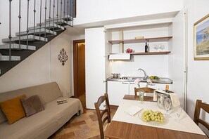 A compact living space with a sofa, dining table, and kitchen area. - Casa Tera A: A graceful two-story apartment in the characteristic style of the Tuscan countryside, with Free WI-FI. (Grosseto)