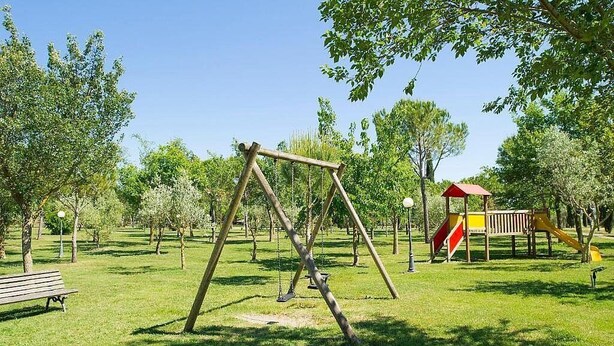 Un parque con un columpio, una banca y juegos infantiles.