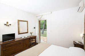 A bedroom with a bed, a TV on a wooden dresser, a mirror, and a door leading to an outdoor area. - Casa Tera A: A graceful two-story apartment in the characteristic style of the Tuscan countryside, with Free WI-FI. (Grosseto)