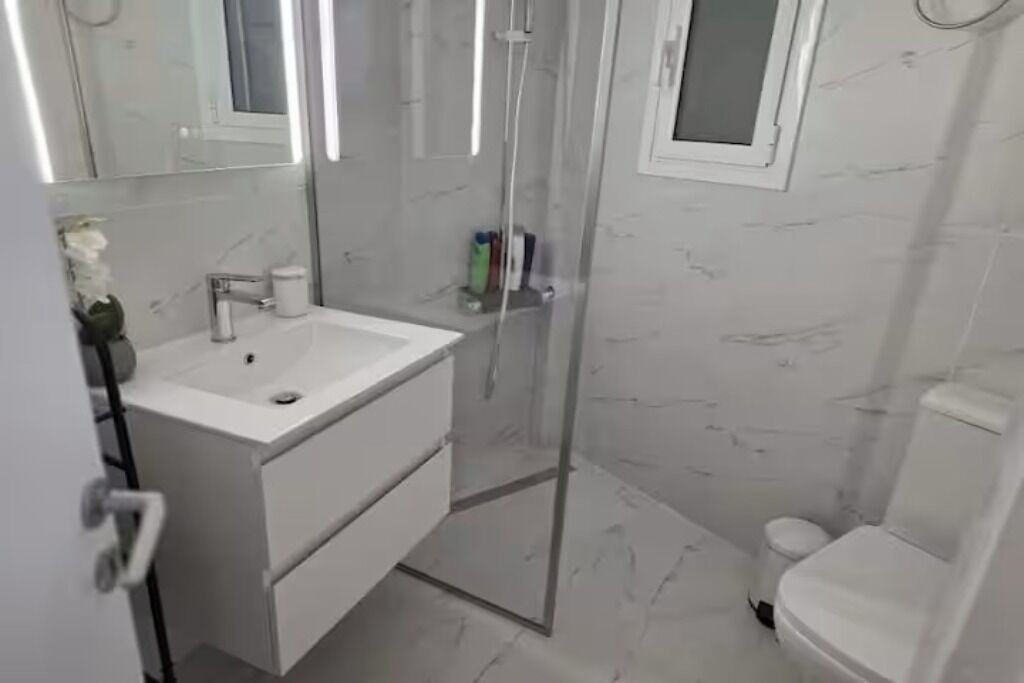 A bathroom with a white sink, mirror, and toilet.