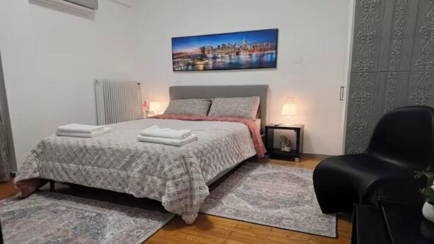 Ein Schlafzimmer mit einem Bett, einem Nachttisch, einem Stuhl und einer Heizung.