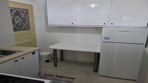 Eine kleine Küche mit weißen Schränken, einem Kühlschrank und einem Spülbecken.