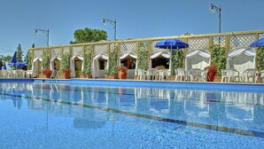 A swimming pool with lounge chairs and umbrellas, surrounded by a covered patio area. - Casa Tera B: A graceful two-story apartment in the characteristic style of the Tuscan countryside, with Free WI-FI. (Grosseto)