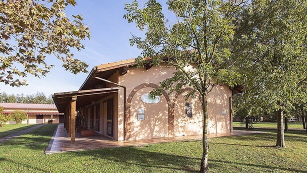 A building with a covered porch, a brick wall, and a tree in front. - Casa Tera B: A graceful two-story apartment in the characteristic style of the Tuscan countryside, with Free WI-FI. (Grosseto)