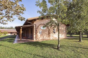 A building with a covered porch, a brick wall, and a tree in front. - Casa Tera B: A graceful two-story apartment in the characteristic style of the Tuscan countryside, with Free WI-FI. (Grosseto)