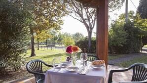An outdoor dining area with a table set for two, surrounded by chairs, with a view of a park and trees. - Casa Tera B: A graceful two-story apartment in the characteristic style of the Tuscan countryside, with Free WI-FI. (Grosseto)