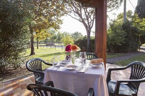 An outdoor dining area with a table set for two, surrounded by chairs, with a view of a park and trees. - Casa Tera B: A graceful two-story apartment in the characteristic style of the Tuscan countryside, with Free WI-FI. (Grosseto)