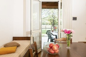 A room with a bed, a dining table with a vase of flowers, and a bowl of fruit. - Casa Tera B: A graceful two-story apartment in the characteristic style of the Tuscan countryside, with Free WI-FI. (Grosseto)