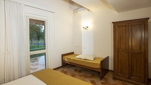 A room with a bed, a wardrobe, a window with curtains, and a door leading outside. - Casa Tera B: A graceful two-story apartment in the characteristic style of the Tuscan countryside, with Free WI-FI. (Grosseto)