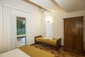 A room with a bed, a wardrobe, a window with curtains, and a door leading outside. - Casa Tera B: A graceful two-story apartment in the characteristic style of the Tuscan countryside, with Free WI-FI. (Grosseto)