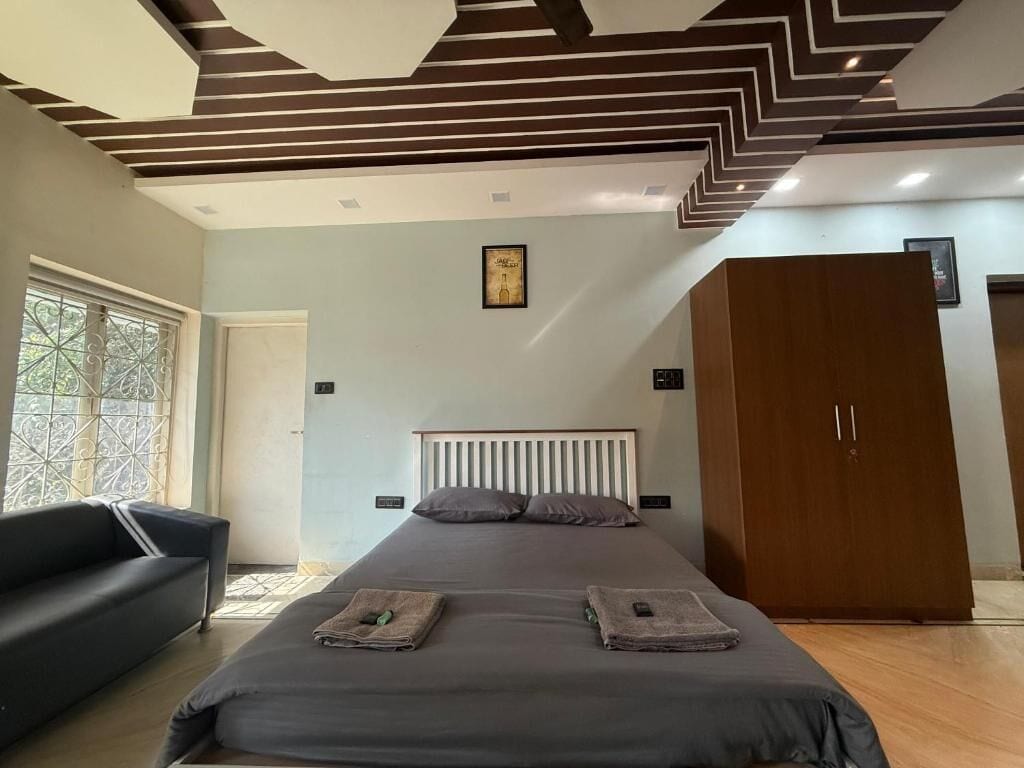 A bedroom with a bed, a wardrobe, a sofa, and a window with a view.