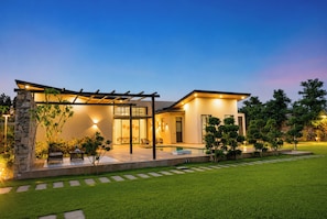 Uma casa moderna com fachada de pedra, um alpendre coberto e uma piscina.