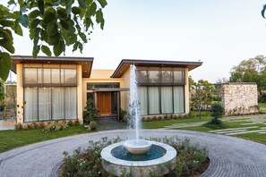 Une maison moderne à deux étages, dotée d’un élément décoratif central avec de l’eau et d’un mur en pierre.