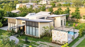 Una zona residencial moderna con varias casas, una piscina y jardines bien cuidados.