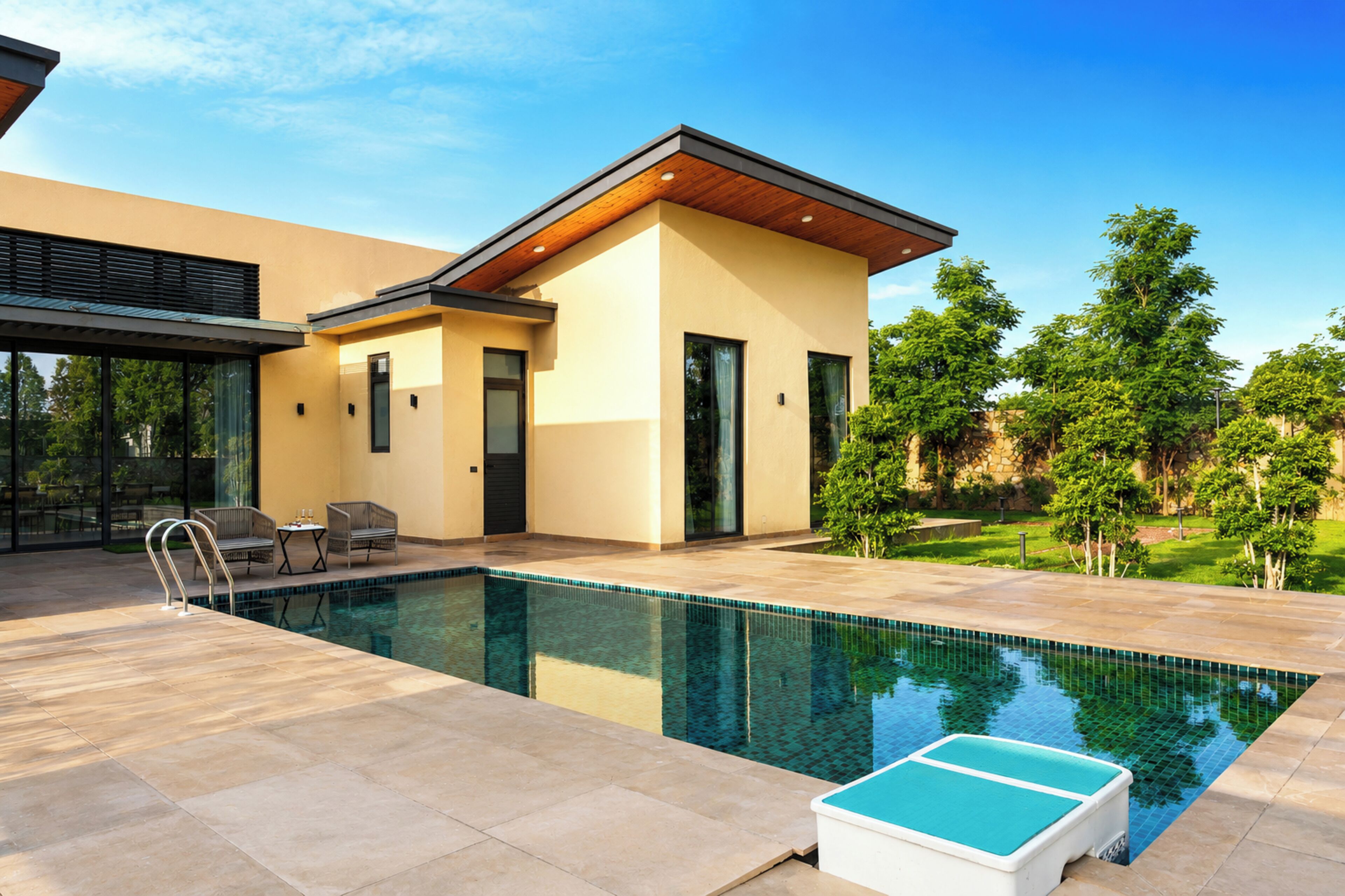 A modern house with a swimming pool, outdoor seating, and a well-maintained garden.