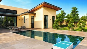 Una casa moderna con piscina, mobiliario de exterior y un jardín bien cuidado.