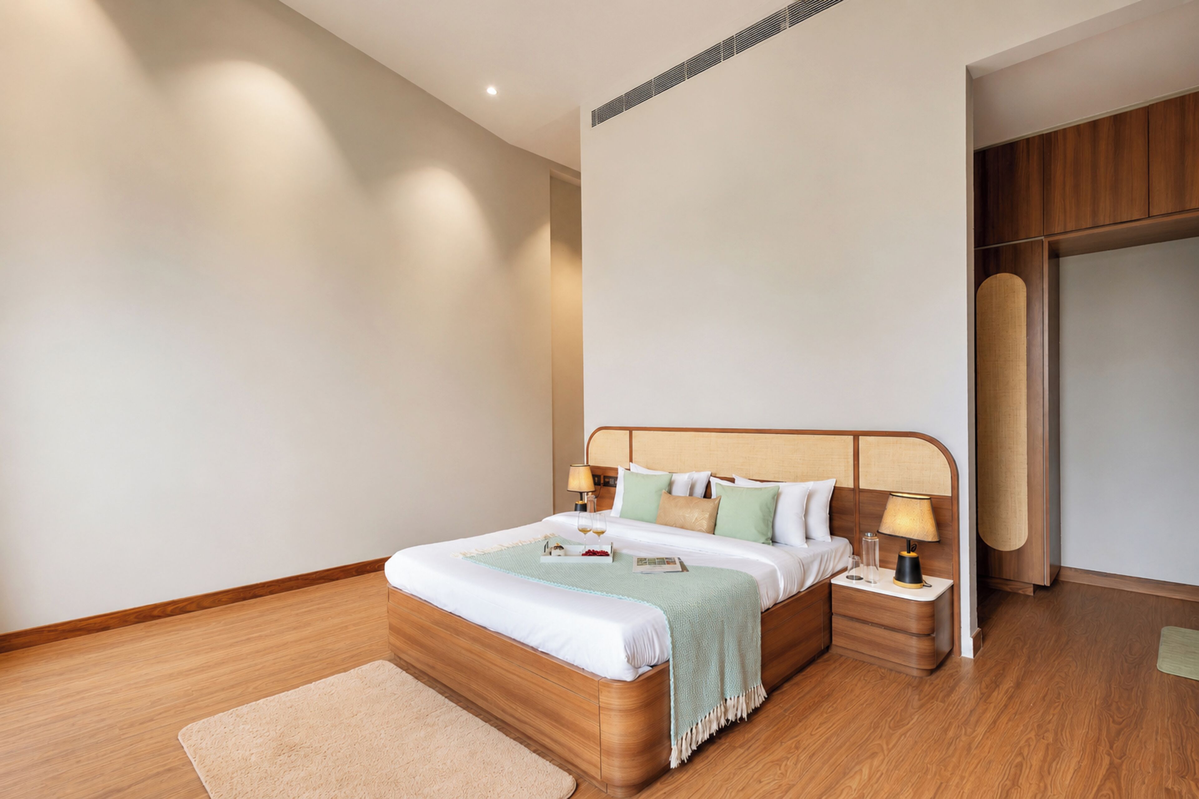 A modern hotel room with a wooden bed, bedside tables, and a neutral color scheme.