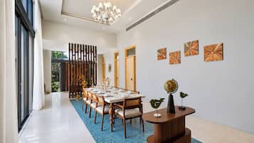 Un comedor amplio con una mesa larga, sillas de madera y un tapete azul con estampado.