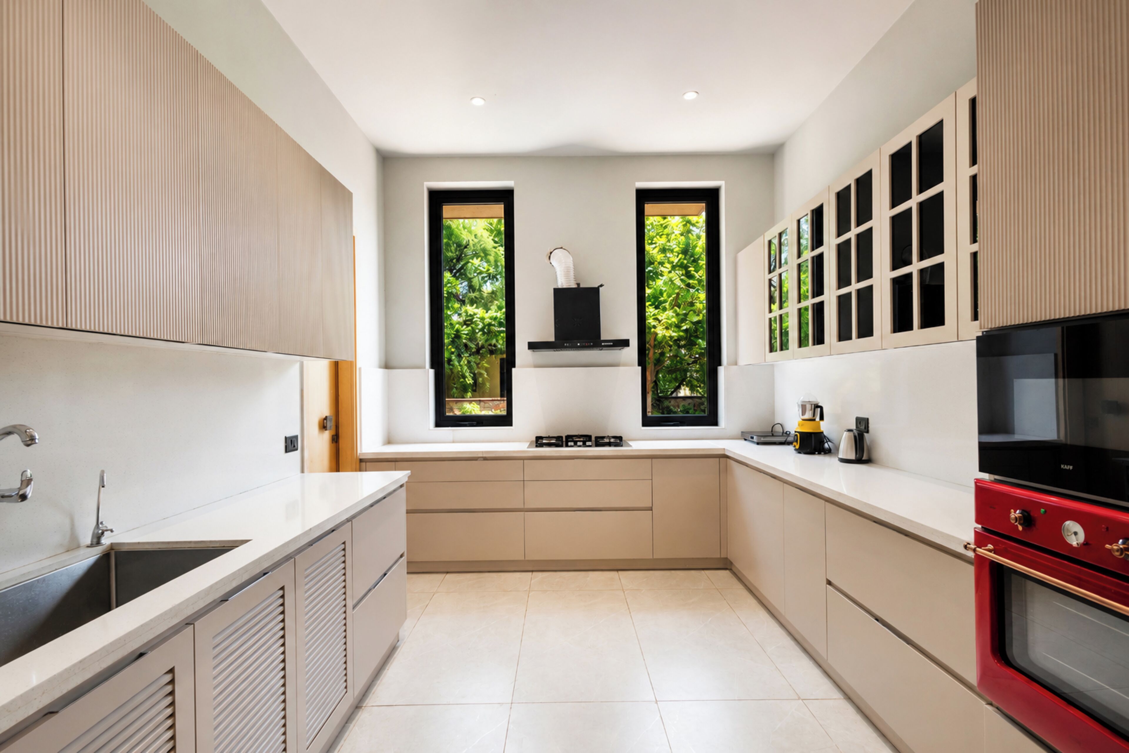 A modern kitchen with a central island, a built-in oven, and a window overlooking greenery.