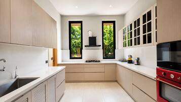 A modern kitchen with a central island, a built-in oven, and a window overlooking greenery.