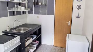 A compact kitchen with a stove, sink, and white refrigerator.
