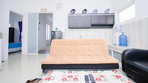 Een kamer met een bed, een slaapbank, een waterdispenser, een klok en een kast met decoratieve borden.