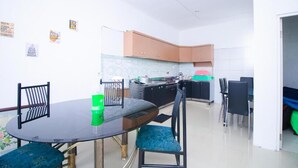 Een kleine keuken met een eethoek, met een ronde tafel, stoelen en een klein kookeiland met een spoelbak.