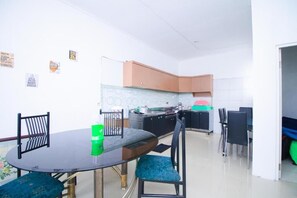 A compact kitchen with a dining area, featuring a round table, chairs, and a small island with a sink. - Cozzy Villa Biru (Jawa Timur)