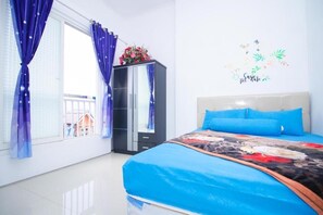 A bedroom with a bed, a wardrobe, a window with curtains, and a wall decoration. - Cozzy Villa Biru (Jawa Timur)