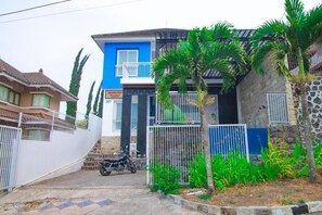 A residential property with a blue and grey facade, a gated entrance, and a motorcycle parked in the driveway. - Cozzy Villa Biru (Jawa Timur)