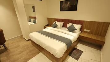 A hotel room with a bed, a nightstand, a mirror, and a wall-mounted artwork.