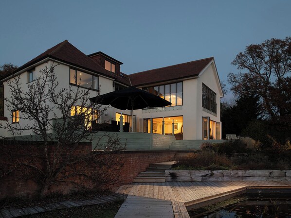 Ein modernes, zweistöckiges Haus mit einer großen Terrassenfläche, einem Schwimmbecken und einem hellen Innenraum.