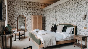 Un dormitorio con cama, armario de madera, espejo, silla y mesita de noche.