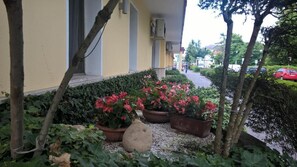 A building with a yellow facade, potted plants, and a gravel pathway. - Hotel Terme Belvedere (Abano Terme)