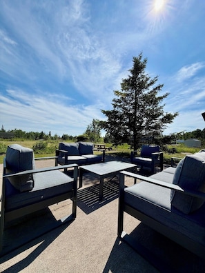 An outdoor seating area with a table and chairs, a picnic table, and a large tree in the background. - 1818 Trailside Cedar - Cabin 2 (Grand Marais)
