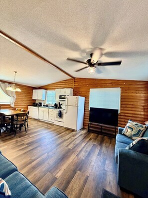 A compact living space with a dining area, kitchenette, and a seating area with a television. - 1818 Trailside Cedar - Cabin 2 (Grand Marais)