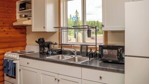 Una cocina con estufa, lavamanos y cafetera.