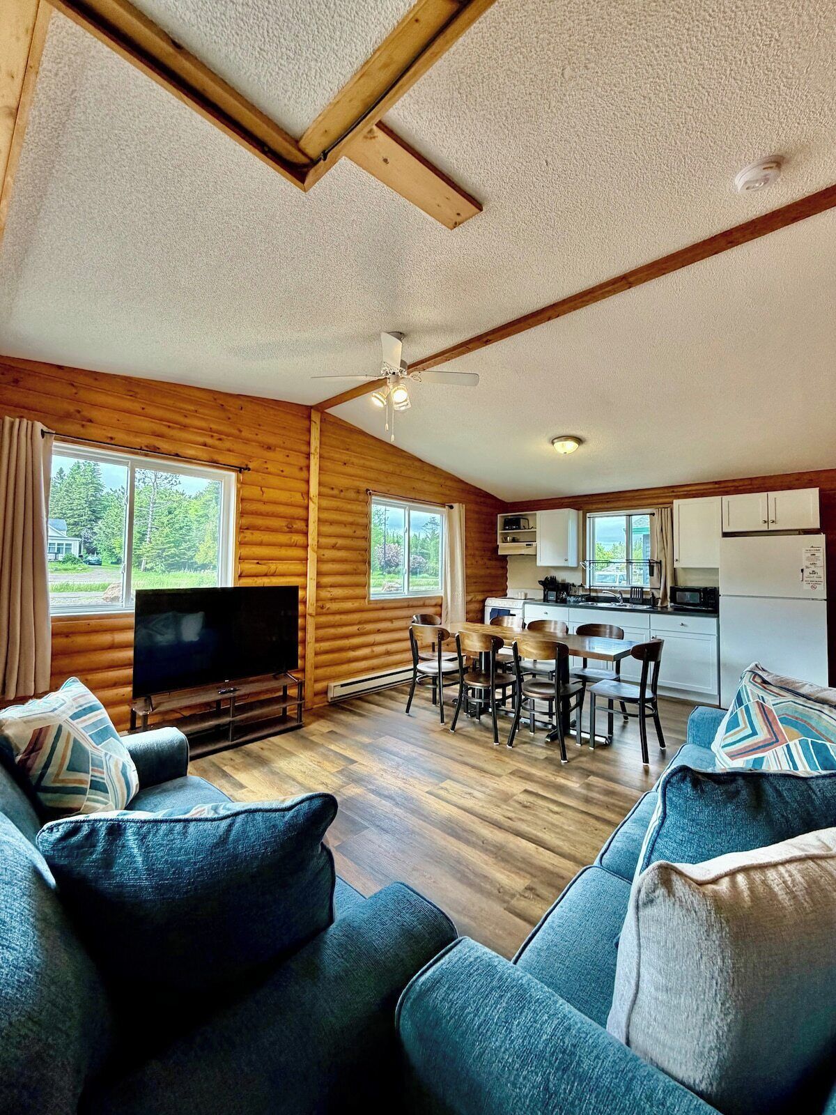 A cozy cabin interior with a TV, sofa, dining area, and kitchen.