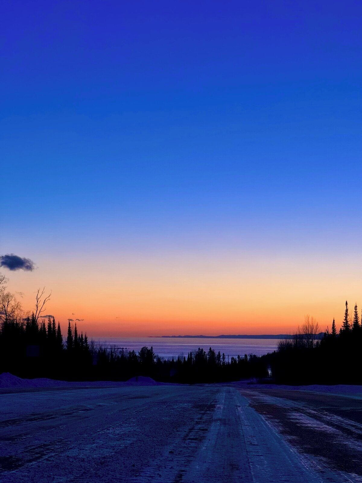 A road leading to a body of water with a clear sky above.