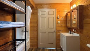 Une petite salle de bain aux murs en bois, avec une porte blanche, un lavabo et des toilettes.