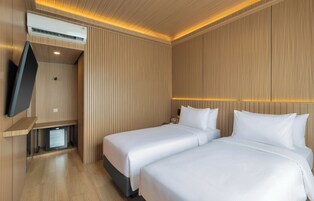Habitación de hotel con dos camas, un televisor de pantalla plana y aire acondicionado.