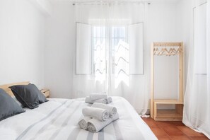 Ein Hotelzimmer mit einem Bett, einer hölzernen Bank und einem Kleiderständer.