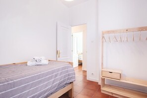 Ein Schlafzimmer mit einem Bett, einer hölzernen Bank und einer Tür zu einem anderen Raum.