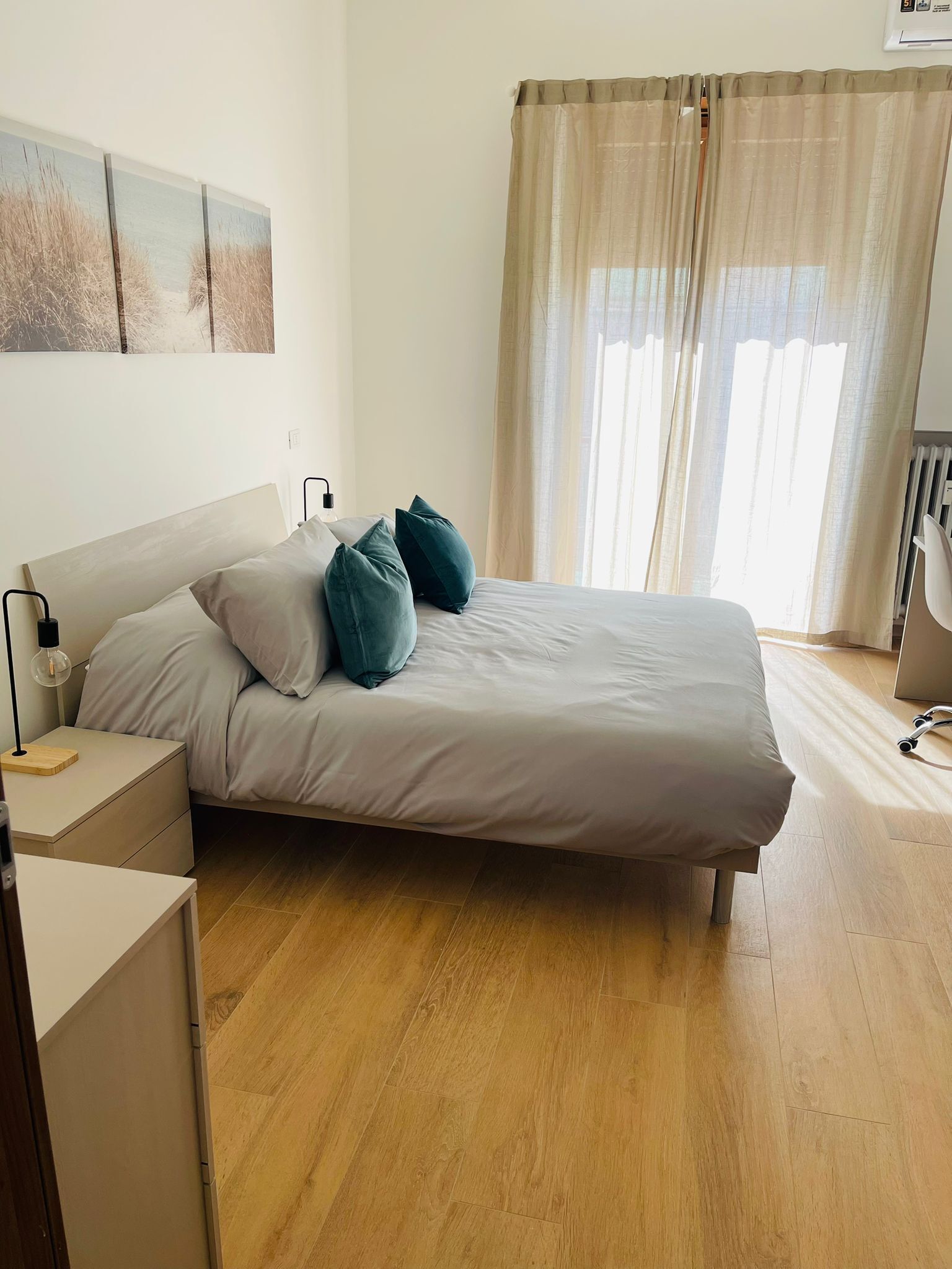 A bedroom with a bed, bedside tables, a lamp, and a radiator.
