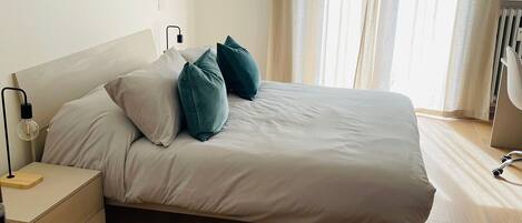 A bedroom with a bed, bedside tables, a lamp, and a radiator.
